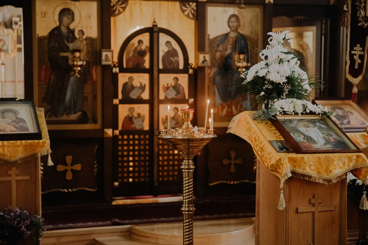 Orthodox church iconostasis with a lit candle stand and a lectern holding an icon