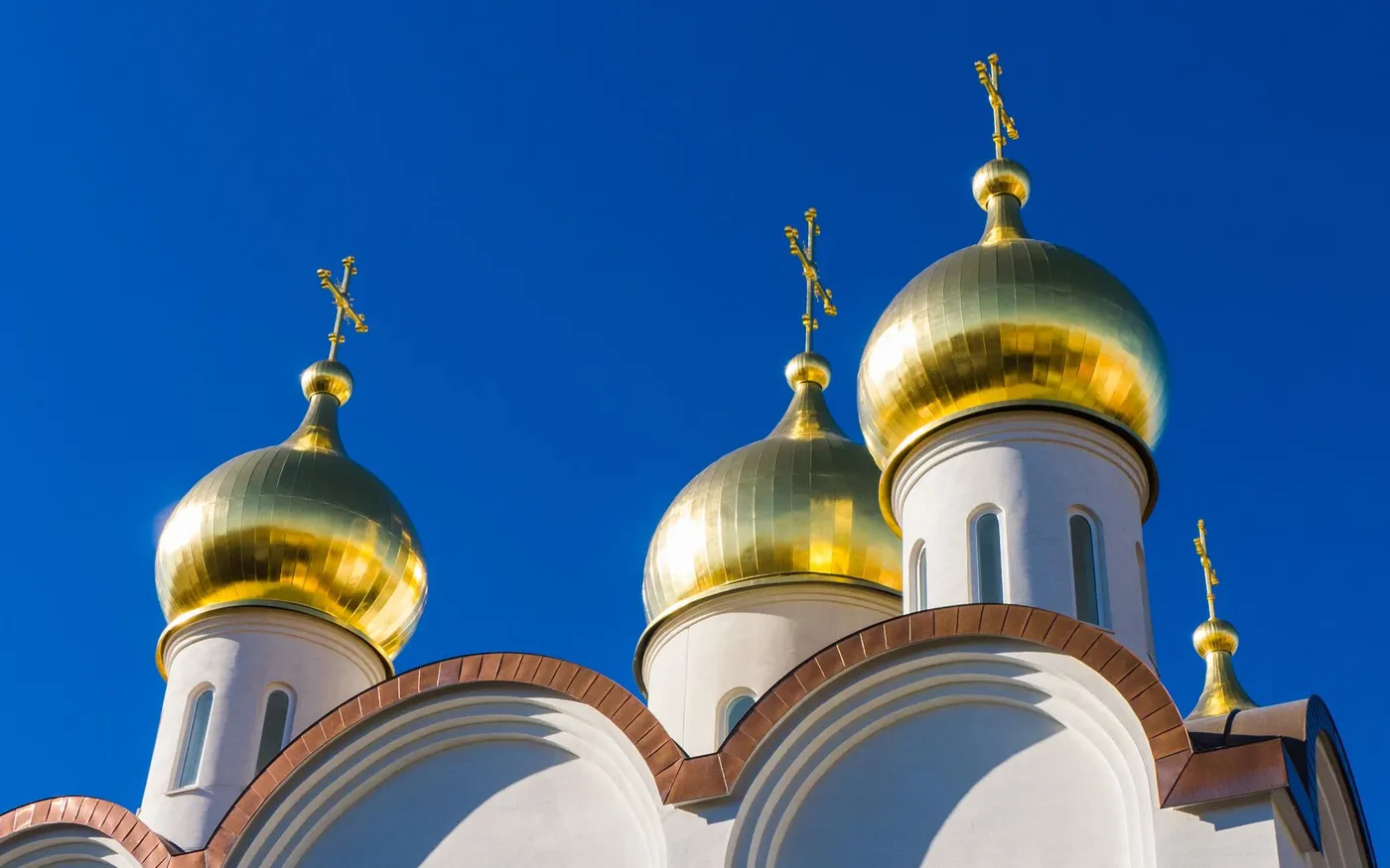 Golden domes and crosses of a Russian Orthodox church against a blue sky